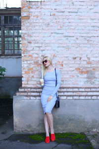 Beautiful woman standing by wall