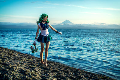 Full length of woman standing at beach against sky during sunset