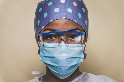 Portrait of doctor wearing mask against blue background