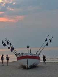 People at beach against sky during sunset