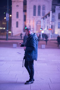 Man using smart phone on city street at night