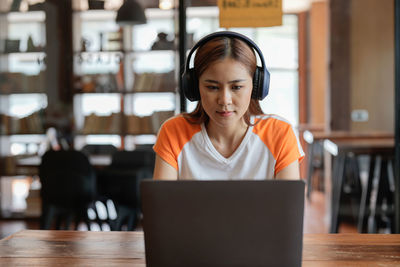 Young woman using laptop at cafe