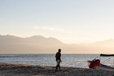 People on beach against sky during sunset