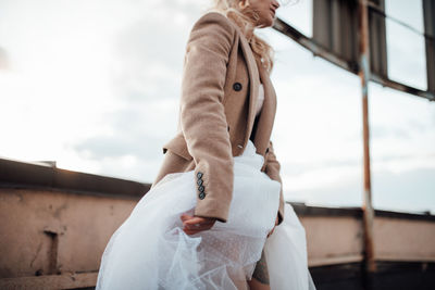 Side view of woman standing against sky