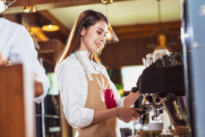 Young woman making coffee in cafe