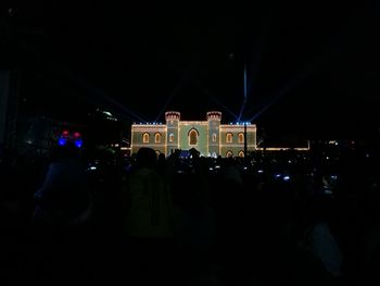 Crowd at illuminated city against sky at night