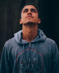 Portrait of young man standing against black background