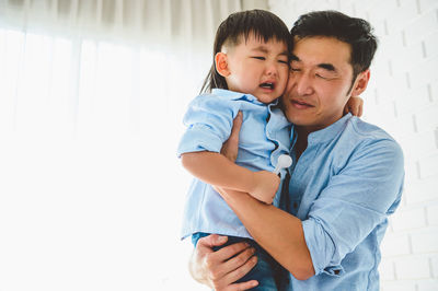 Father and son with daughter against wall