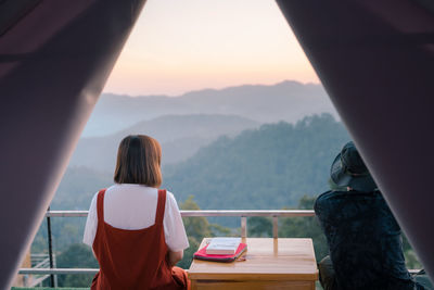 Rear view of woman looking through window