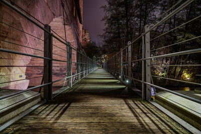 Footbridge amidst trees at night