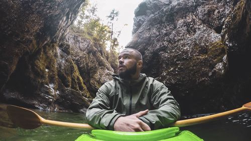 Young man kayaking amidst rock formation