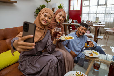 Friends using mobile phone while sitting at home