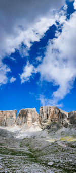 Low angle view of rocks on mountain against cloudy sky