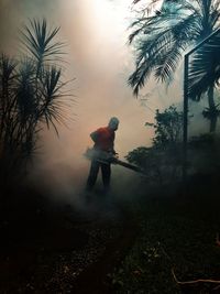 Man standing by palm tree on field against sky