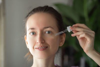 Portrait of young woman holding thermometer