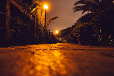 Illuminated street light against sky at night