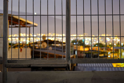 Metal fence against illuminated building seen through window