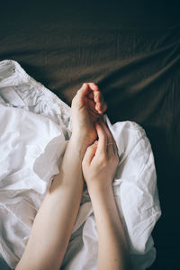 Cropped hands of woman on bed at home