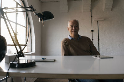 Portrait of smiling senior businessman sitting at desk in office