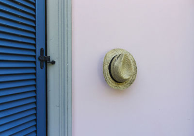 Straw hat hanging on wall by door at home