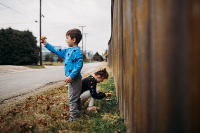 Young brother and sister picking flowers on a walk outside