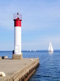 Lighthouse by sea against sky