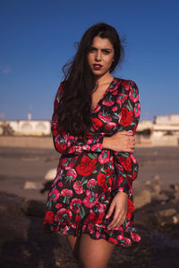 Beautiful young woman standing against sky