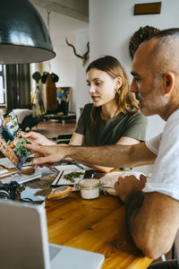 Male and female entrepreneurs discussing while looking at photograph in studio