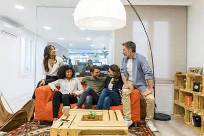 Relaxed male and female entrepreneurs sitting on sofa in lobby at office