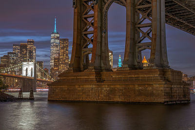 Illuminated bridge over river against sky at night