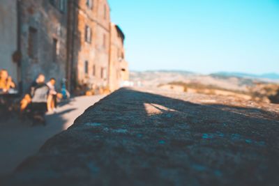 Surface level of street amidst buildings against clear blue sky