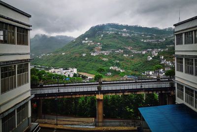 Bridge by buildings in city against sky