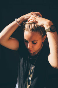 Close-up of young woman against black background