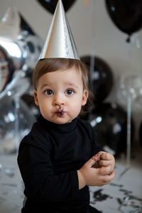 Boy stands next to a festive black cake and balloons