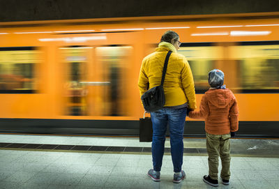 Rear view of mother with son at railroad station