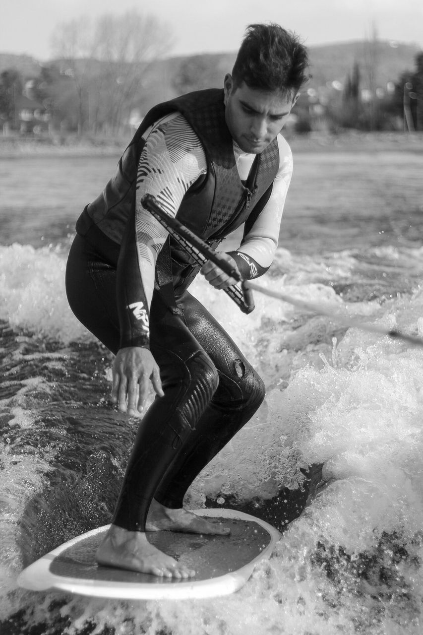 black and white, one person, black, monochrome photography, monochrome, adult, full length, sports, men, nature, water, white, lifestyles, young adult, motion, leisure activity, person, clothing, day, activity, surfing, land, outdoors