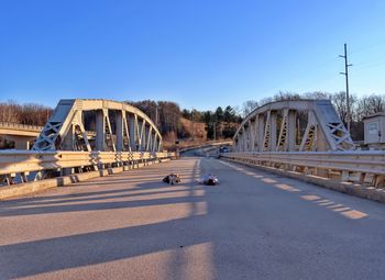 Bridge over road against clear blue sky