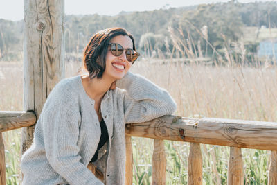 Portrait of young woman standing by railing