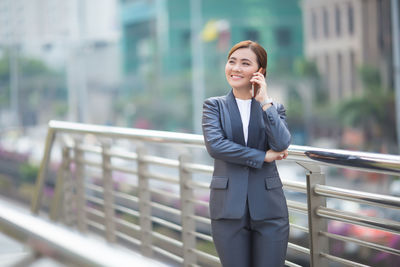 Full length of a young woman using phone in city