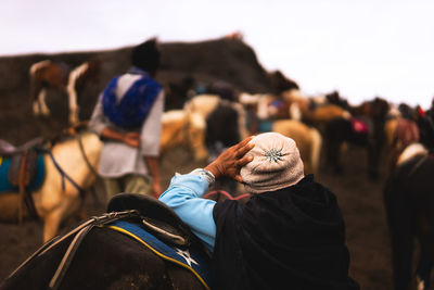 Rear view of man leaning on horse at mt bromo