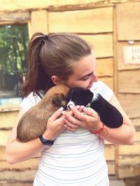 Woman embracing while holding puppies against wall