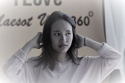 Beautiful young woman looking away while standing against text