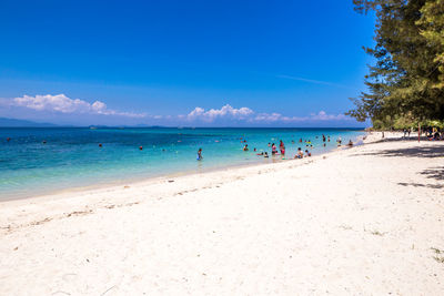 Group of people on beach against blue sky