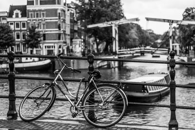 Bicycle parked by railing on bridge over canal