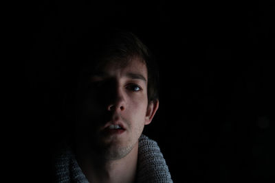 Close-up portrait of young man against black background