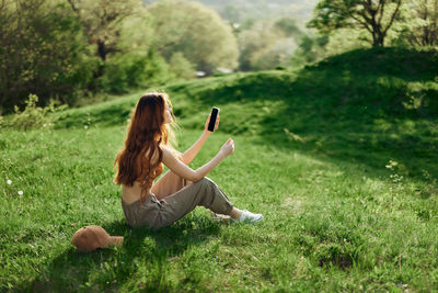 Rear view of woman sitting on grassy field