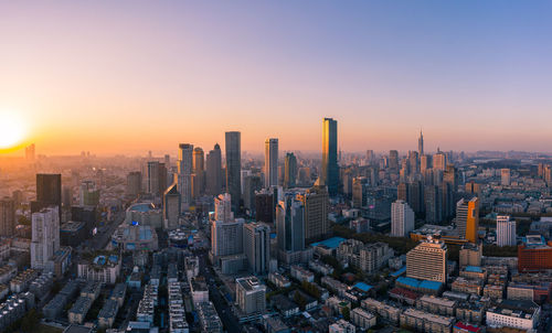 Aerial view of modern buildings in city against sky during sunset