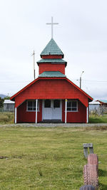 Red wooden church on green field against sky