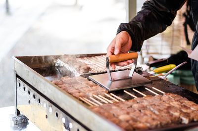 Close-up of man preparing food on barbecue grill