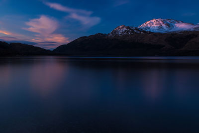 Scenic view of lake by mountains against sky